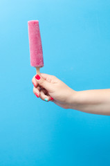 Tasty ice cream in a female hand on a blue background