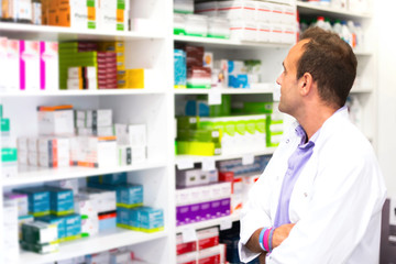 Adult man pharmacist in pharmacy looking for medications