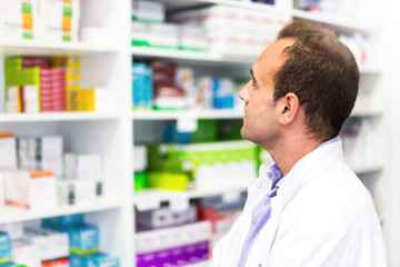 Adult man pharmacist in pharmacy looking for medications