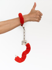Female sexy hands in fur red handcuffs on a white background. Sex toys.