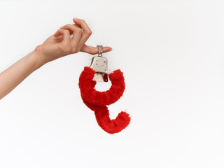 Female sexy hands in fur red handcuffs on a white background. Sex toys.