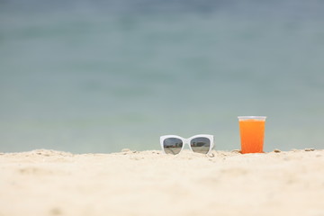 summer background, sunglasses and drink on the beach sand
