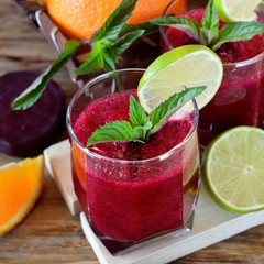 Smoothie with beet and orange in a glass decorated with mint and a slice of lime
