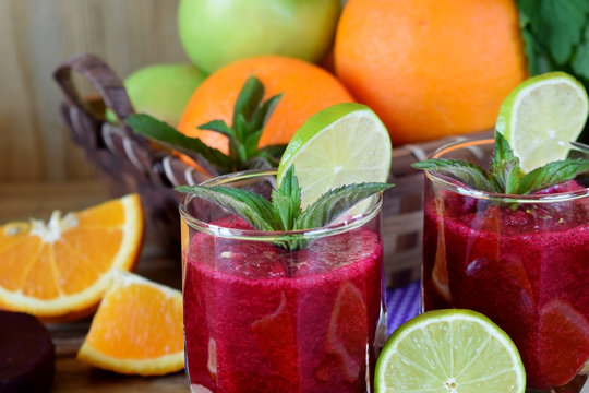 Smoothie with beet and orange in a glass decorated with mint and a slice of lime