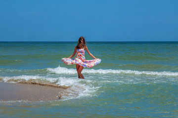 Young beautiful woman dancing in water of sea as symbol of freedom and happiness.
