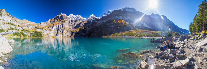 Amazing tourquise Oeschinnensee lake with waterfalls, wooden chalet and Swiss Alps, Berner...