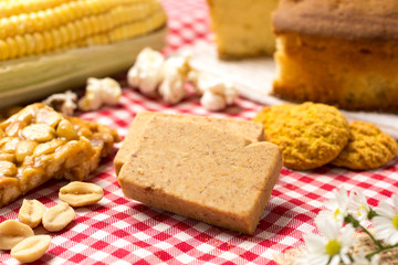 Pacoca is a candy with peanuts from Brazil. Sweet food of Festa Junina, a typical brazilian party. Red plaid fabric on table.