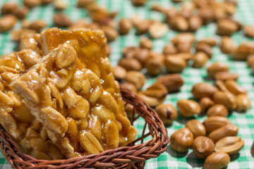 Candy with peanut: Pe de Moleque in Brazil and Chikki in India. Sweet food of Festa Junina, a typical brazilian party. Snack on wicker basket and green background.