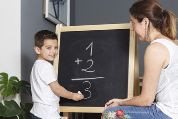 Mother teaches her son math at home with a blackboard 