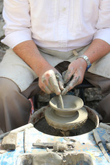 Traditional crafts - skilled professional potter making a piece of pottery of clay on potter´s wheel