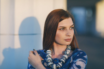 Young stylish girl looks away thoughtfully. Portrait of model in sunset sunlight