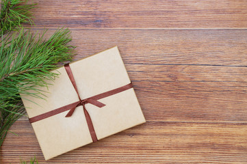 Christmas gift in a kraft box with ribbon on a brown wooden background. Place for text