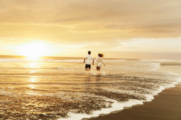 A couple in love running towards sunset