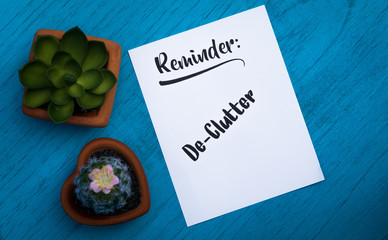 Reminder De-Clutter motivational concept on white paper and blue table flat lay in vintage tones