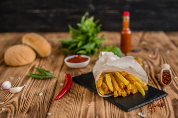 Tasty French Fries with vegetables against a dark background. Fast food. It can be used as a background