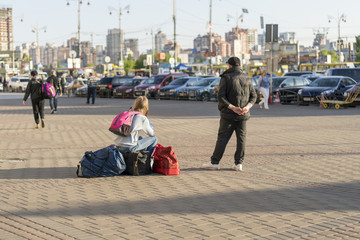 Girl with suitcases on the city street. A young woman with suitcases is waiting for a taxi on the city street