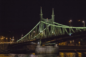 View on the Liberty bridge footing of Chain bridge on Danube river at night in Budapest, Hungary