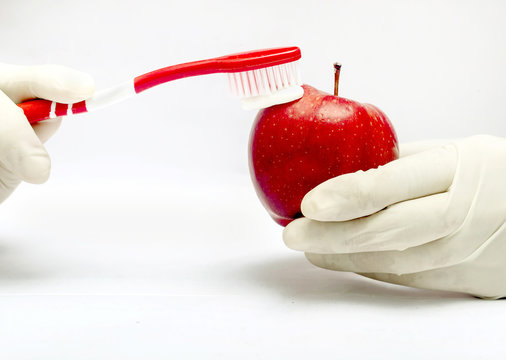 Tooth brushing tecnique with toothpaste  and red apple isolated in white background
