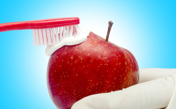 Tooth brushing tecnique with toothpaste  and red apple isolated in white background