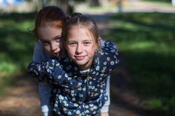 Two girls sisters or girlfriends having fun outdoors. Looking into the camera.