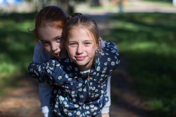 Fototapeta premium Two girls sisters or girlfriends having fun outdoors. Looking into the camera.