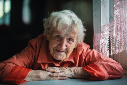 Old woman sitting near window, close-up portrait.