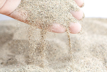 Sand is poured from women's hands. Macro