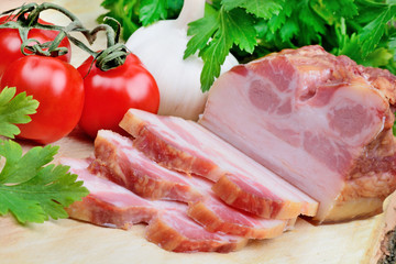 Sliced of bacon with cherry tomatoes and garlic on table