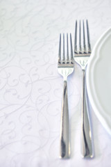 Forks and plates on a white tablecloth