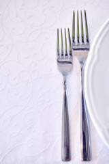 Forks and plates on a white tablecloth