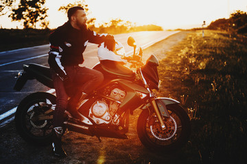 Full length portrait of an awesome young caucasian man sitting on his motorcycle while resting in...