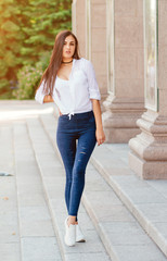 Obraz premium young stylish brunette girl posing in white shirt and jeans