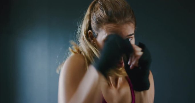 Beautiful athletic woman kickboxing, training in the gym, slow motion