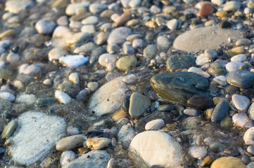pebble stones on the sea beach, the rolling waves of the sea with foam