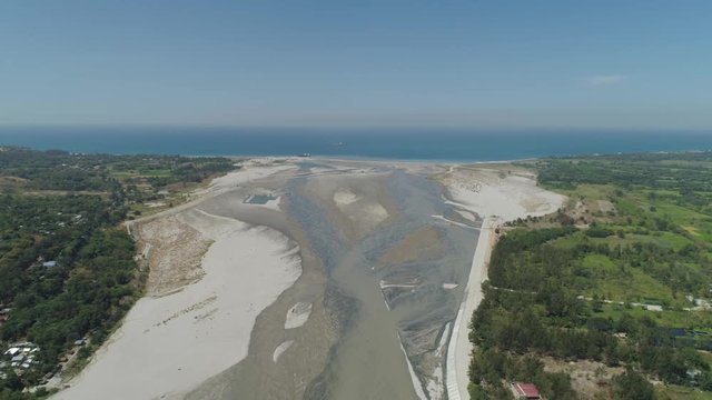 Mountain river Bucao flowing into the sea in Philippines,Luzon. Aerial view river among farmer fields flowing into the blue ocean.