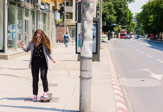Young skater happy teen girl using a smart phone