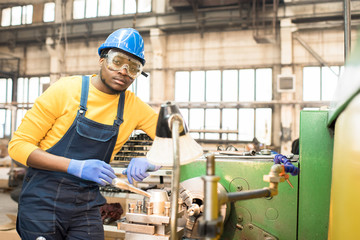 Portrait shot of handsome young lathe operator wearing protective helmet and safety goggles...