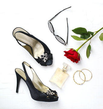 Woman fashion flatlay. Shoes, sunglasses, golden bracelets, parfume and red fresh rose  on white background.