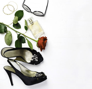 Woman fashion flatlay. Shoes, sunglasses, golden bracelets, parfume and red fresh rose  on white background.