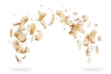 Cashew crushed into pieces, frozen in the air on a white background