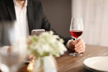 Man with glass of wine at table in restaurant