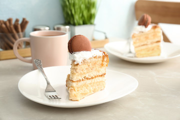 Piece of delicious homemade cake with caramel sauce and macaron on table