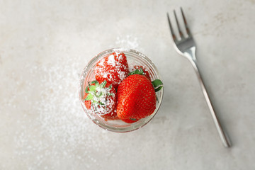 Glass jar with ripe red strawberries on light background, top view