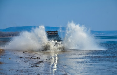 Obraz premium The car goes on water. Splashes from under the wheels. Off-road. Beautiful riding. Car headlight.
