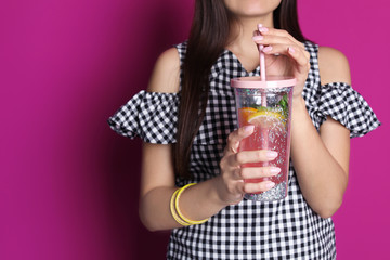 Young woman with tasty lemonade on color background. Natural detox drink