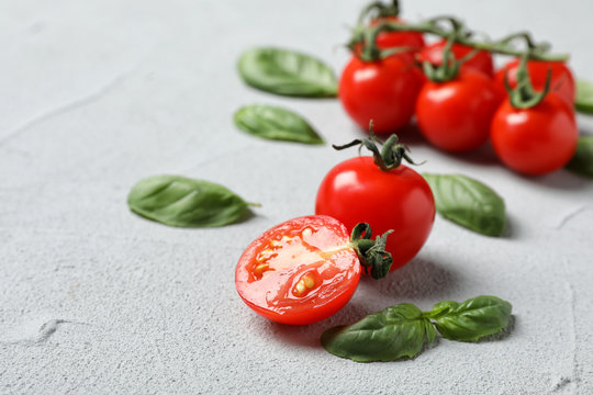 Ripe red tomatoes and basil on grey table, closeup
