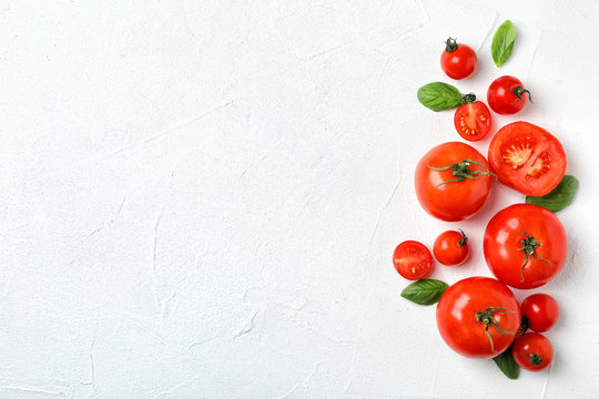 Flat lay composition with tomatoes and basil on light background