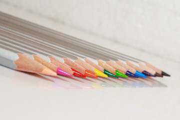 Color pencils lie in a line on white background.
