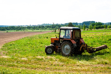  Tractor on the field mows the grass