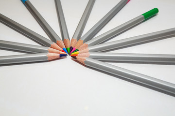 Color pencils lie in a circle on white background